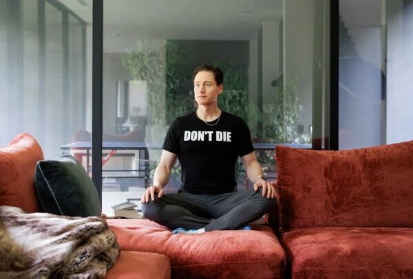 Брайан Джонсон сидит дома, скрестив ноги.