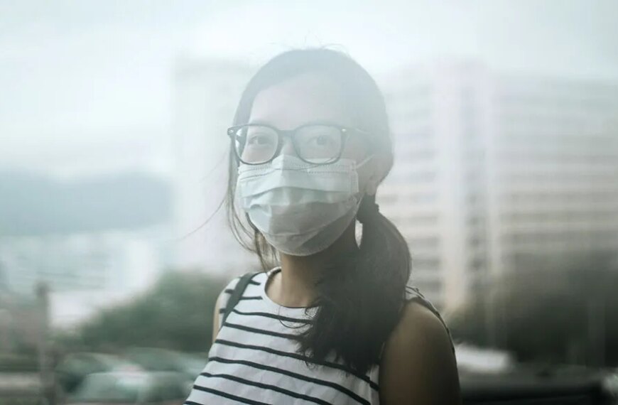 Женщина в полосатой майке на фоне городского пейзажа и зданий.