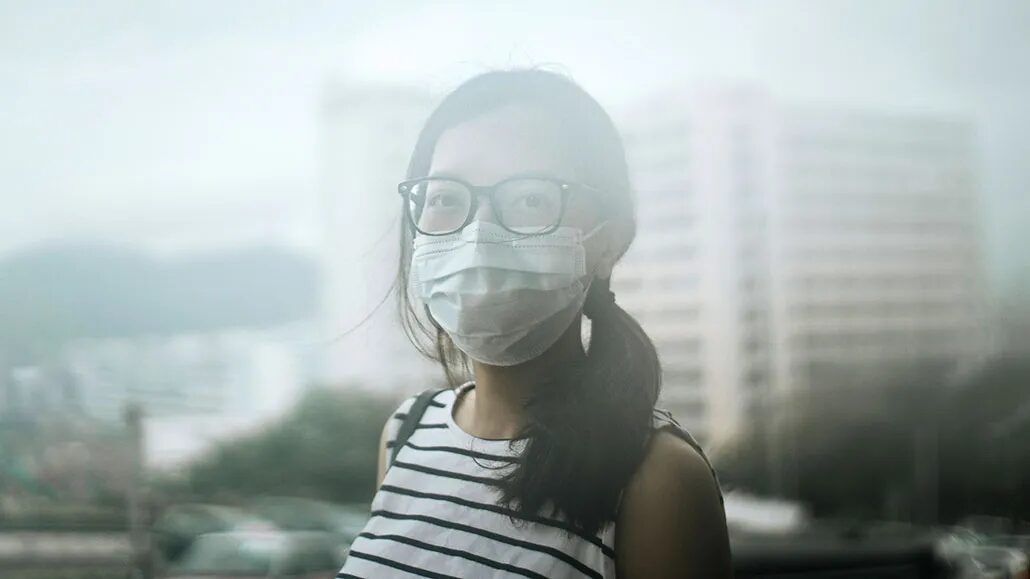 Женщина в полосатой майке на фоне городского пейзажа и зданий.