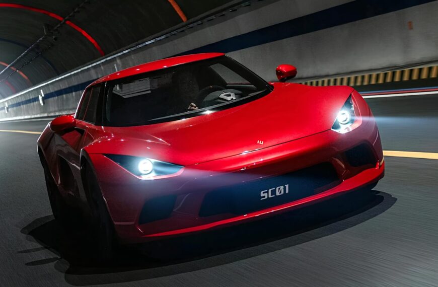 Красный спортивный автомобиль едет по освещенному туннелю.