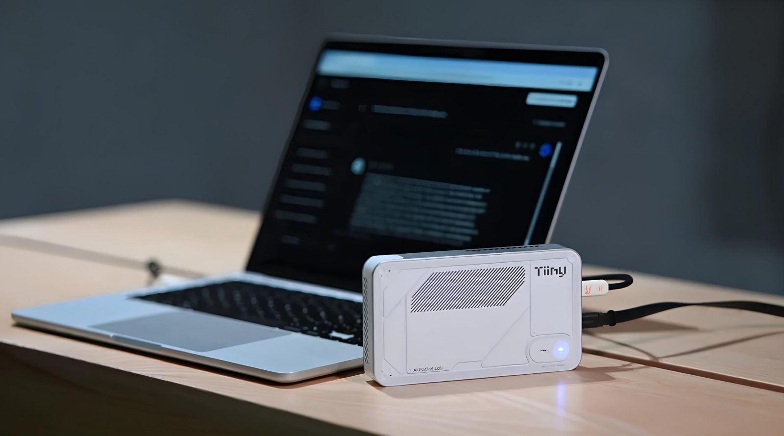 Ноутбук и мини-компьютер Tiiny AI на столе, подключенный к ноутбуку.