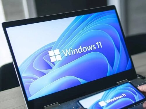 Ноутбук и смартфон с логотипом Windows 11 на экранах, современный интерфейс системы.