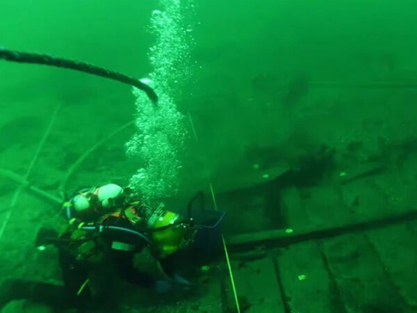 Водолаз исследует затонувший корабль под водой, пузыри воздуха, глубина океана.