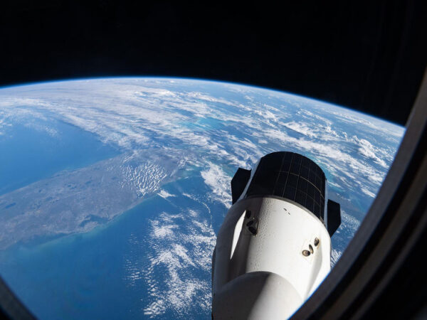 Вид на Землю и космический аппарат из иллюминатора на орбите планеты.
