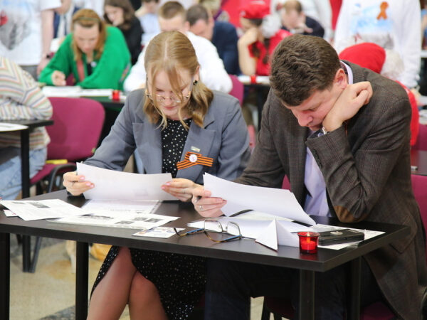 Участники конкурса за столом с бумагами на мероприятии.