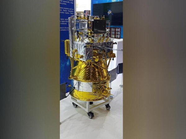 Компонент космического спутника на выставке, блестящий золотой и серебряный корпус.