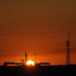 Закат на фоне космодрома и ракетных установок, башни и солнце.