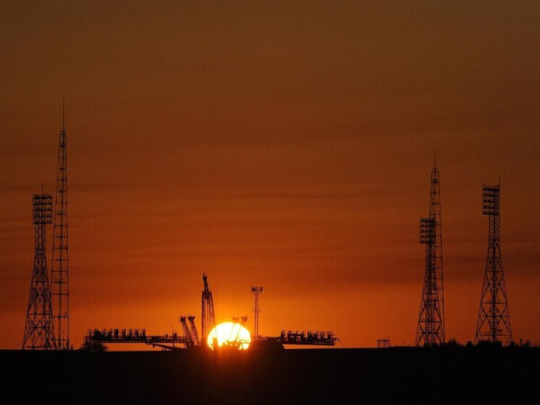 Закат на фоне космодрома и ракетных установок, башни и солнце.