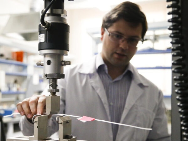 Человек в лаборатории проводит испытания материалов на специальной тестовой машине.