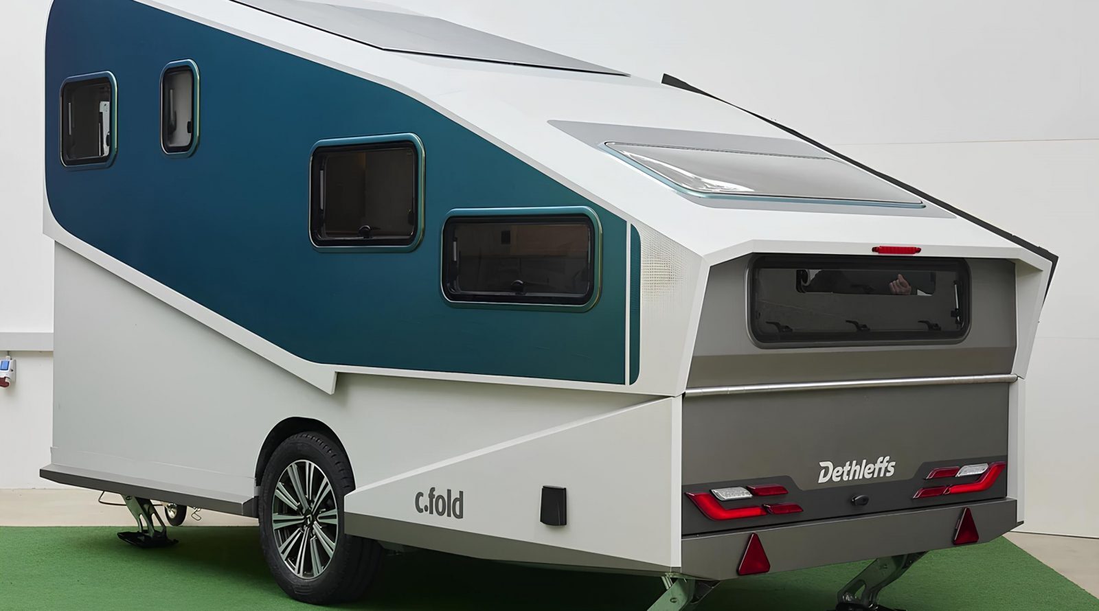 Прицеп будущего: трансформируемый c.fold 2 Современный туристический трейлер с синей облицовкой на стоянке.
