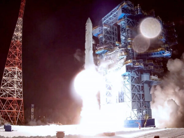 Старт ракеты ночью с космодрома, огни и дым вокруг.