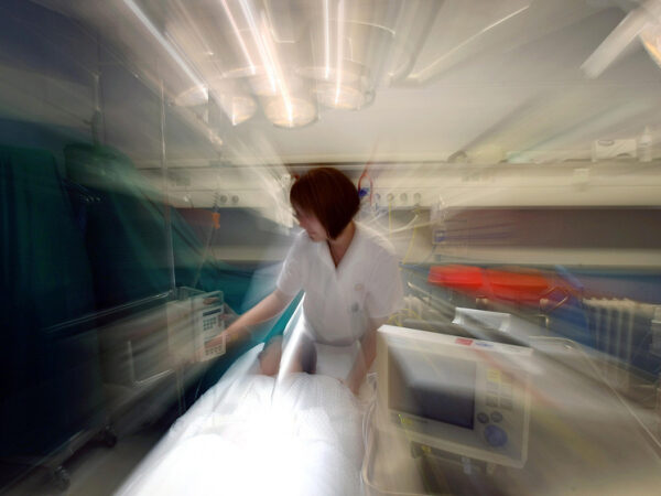 Медицинский работник в больнице возле пациента и оборудования.