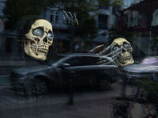 Чёрный автомобиль на улице и отражение скелета в витрине.