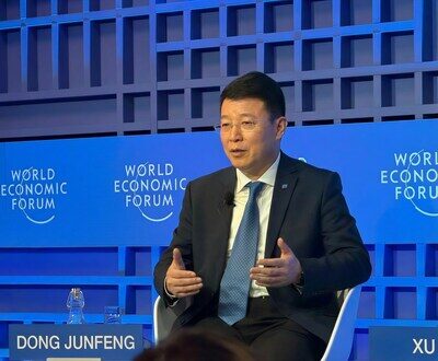 Человек в костюме выступает на Всемирном экономическом форуме на синем фоне.