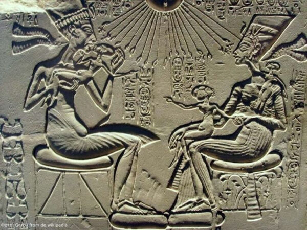 Древнеегипетский барельеф: фараон, жена и дети под солнечным диском с иероглифами.