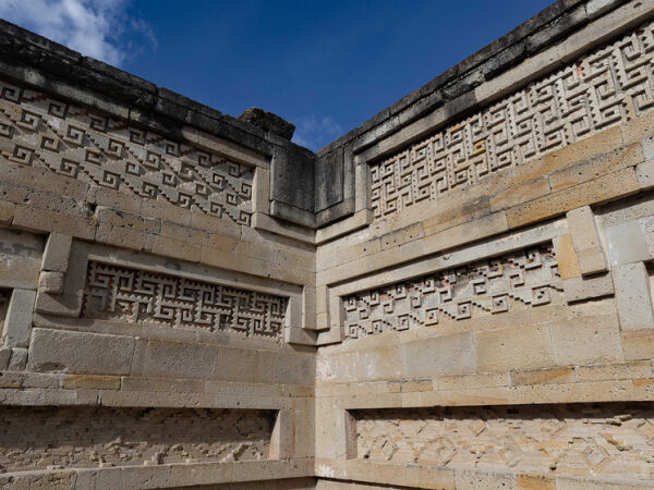 Древняя стена с резьбой в археологическом комплексе под голубым небом.