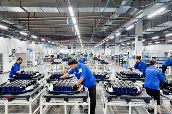 Рабочие собирают аккумуляторы на заводе, промышленное производство, упаковка батарей.