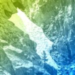 Скалы с разноцветной наслоенной обработкой и снежным участком в ущелье.