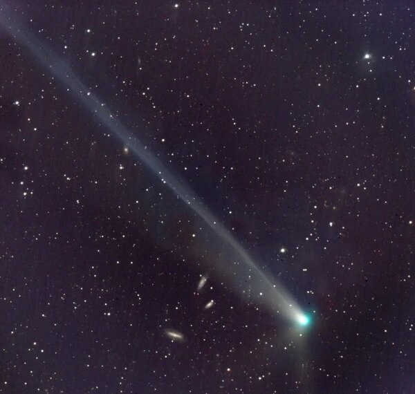 Комета с длинным хвостом на фоне ночного звёздного неба.