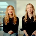 Две женщины с длинными волосами сидят в светлой комнате, одеты в черное.