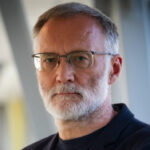 Мужчина в деловой одежде на фоне современного интерьера.