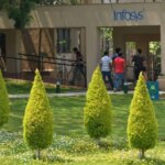 Офис компании Infosys с посетителями на фоне зелёного ландшафта и деревьев.