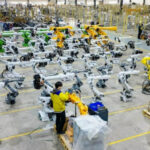 Завод сборки промышленных роботов: работник проверяет роботизированные системы.