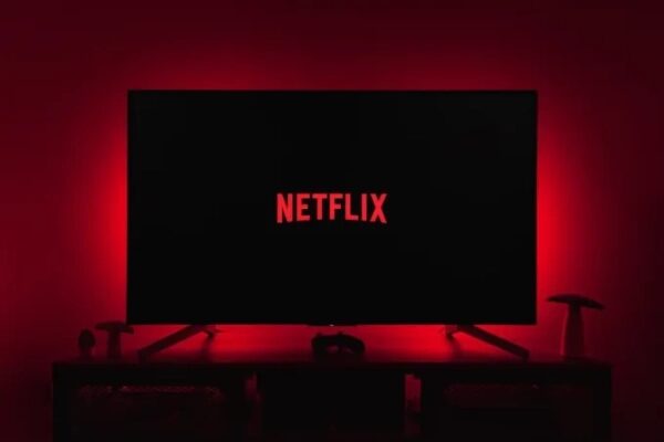 Логотип Netflix на чёрном экране, подсвеченный красным свечением.