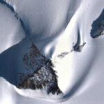 Снежный пейзаж с узорами и тенями, напоминающими форму кошачьей головы.