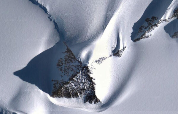 Снежный пейзаж с узорами и тенями, напоминающими форму кошачьей головы.