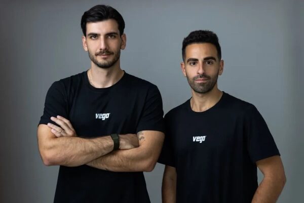 Два человека в черных футболках с логотипом "vego" на сером фоне.