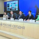 Пресс-конференция в «Россия Сегодня», выступают представители на фоне экрана с графиками.