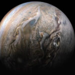 Изображение Юпитера с атмосферными вихрями и бурями на его поверхности.