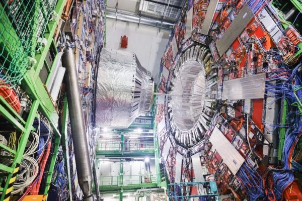 Акселератор частиц в лаборатории, окружённый сложными кабелями и оборудованием.