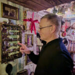 Мужчина в комнате с декором и счетами на стене.