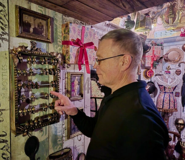 Мужчина в комнате с декором и счетами на стене.