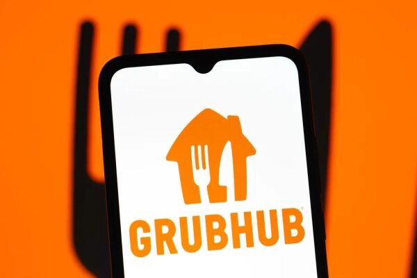 Логотип Grubhub на экране смартфона с оранжевым фоном.