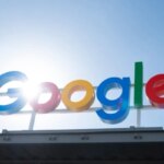 Логотип Google на крыше здания на фоне солнца.