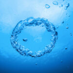 Кольцо из пузырьков под водой на синем фоне.