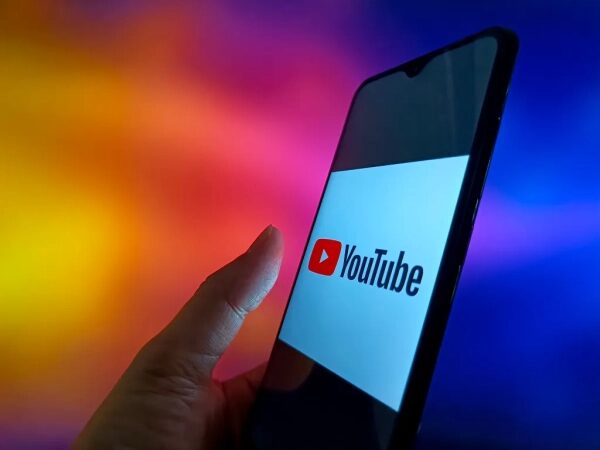 Смартфон с логотипом YouTube на экране, радужный фон.