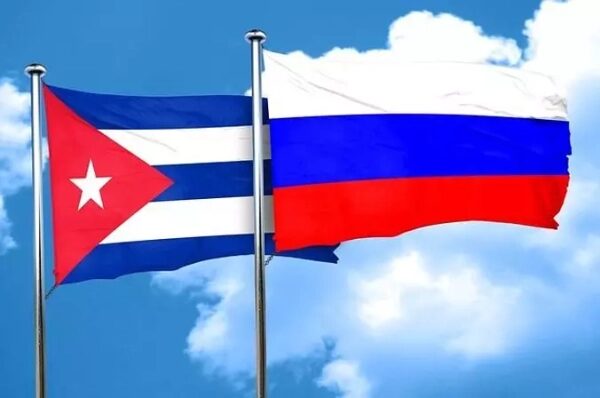 Флаги Кубы и России на фоне облаков, символизирующие международные отношения.