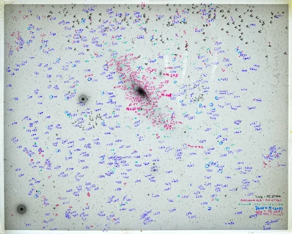 Астрономический фотонегатив галактики обильно исчерчен фиолетовым и красным маркером.