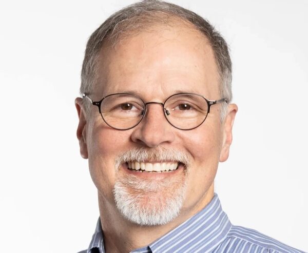 Мужчина в полосатой рубашке на белом фоне.