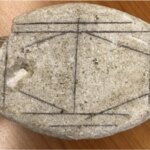 Камень с руническими символами на деревянном фоне.