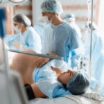 Роды в больнице, медицинская команда в операционной, врачи в защитной одежде.