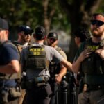 Офицеры HSI обмениваются информацией на открытом воздухе в защитной экипировке.