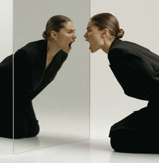 Женщина в черном костюме смотрит в зеркало, создавая интересный визуальный эффект.