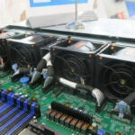 Внутренности серверного оборудования с вентиляторами и компонентами на зеленой плате.