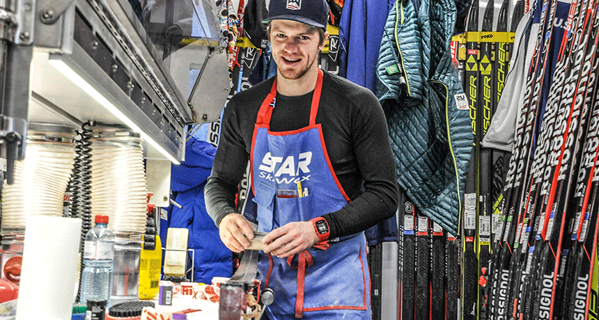 Мастер обрабатывает лыжи в мастерской, окружен снаряжением и инструментами для ухода.