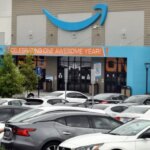 Парковка у входа на склад Amazon, украшенного баннером к годовщине.